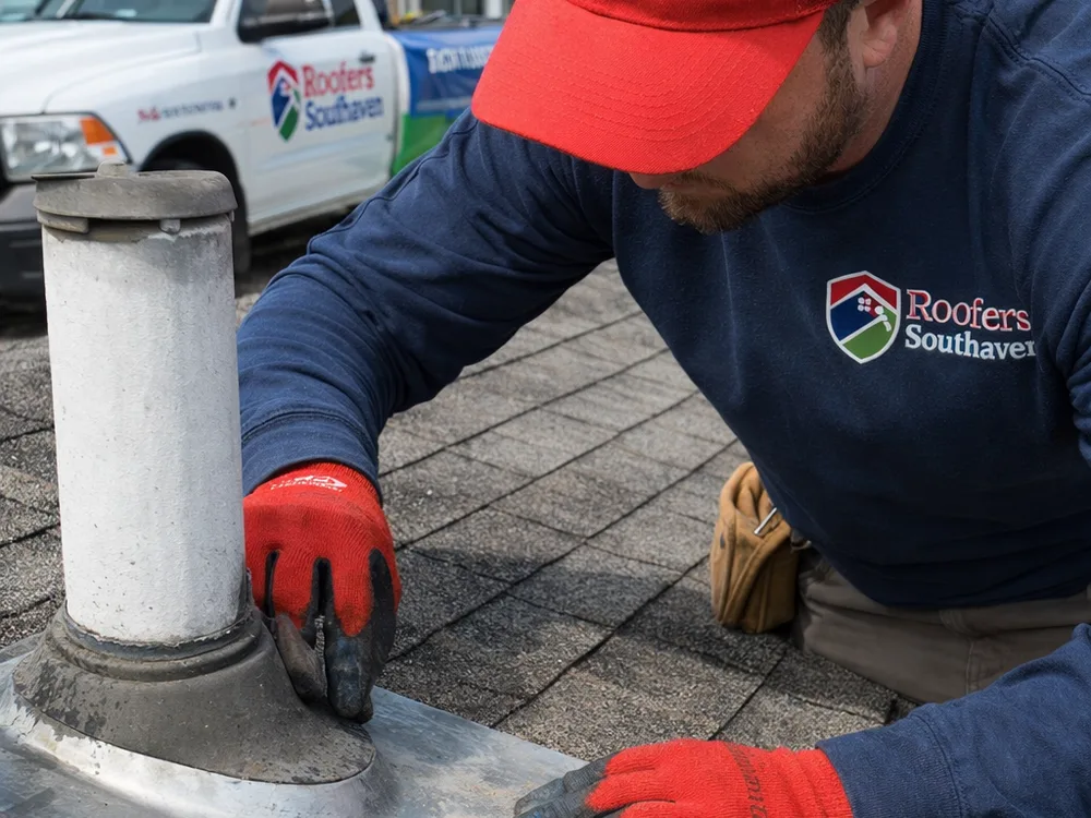 Close-up of roof flashing and a vent pipe boot being inspected for leaks and storm wear
